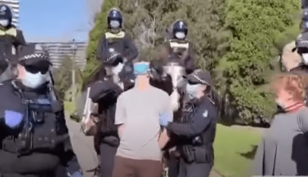 Oto nowa rzeczywistość! Grupa policjantów trzyma jednego człowieka, żeby włożyć mu maseczkę!